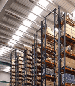 Almacén de hardware tecnológico con racks industriales y equipos de cómputo listos para distribución.