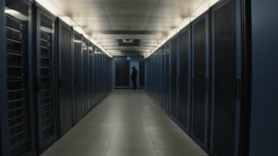 Corredor de data center en penumbra con silueta de ejecutivo al fondo, simbolizando la brecha silenciosa de Oracle EBS explotada por Cl0p mediante CVE-2025-61882