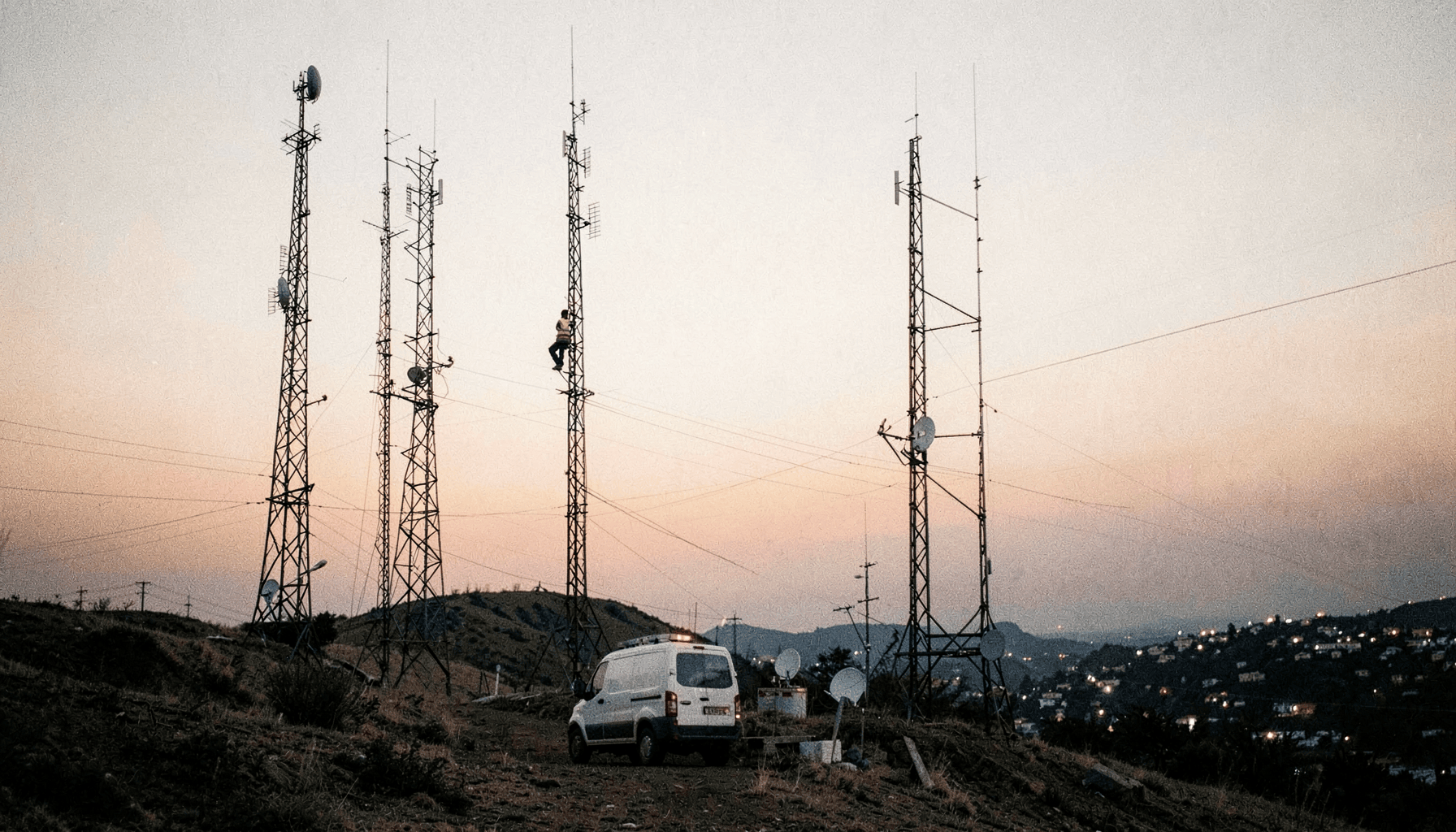 Torres de telecomunicaciones en una loma al atardecer con un técnico subiendo, ilustración del artículo sobre firmware malicioso preinstalado