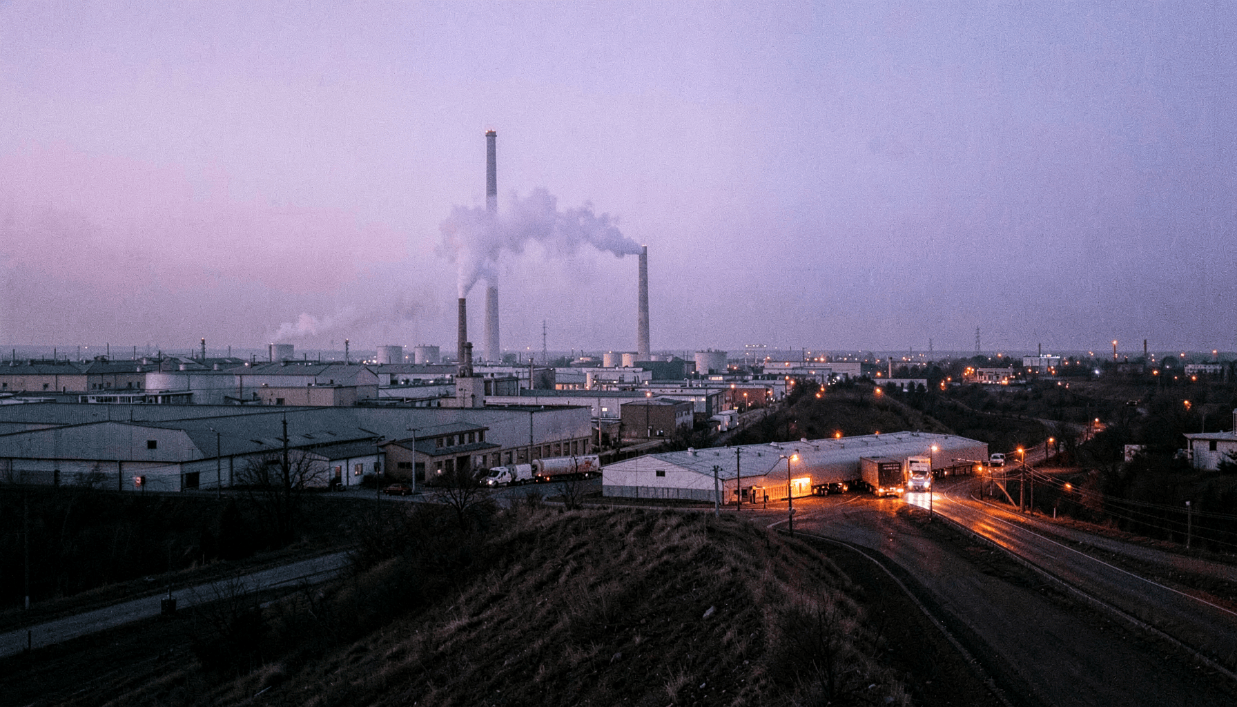 Parque industrial al anochecer con chimeneas, tanques y camiones esperando en la entrada, ilustración del artículo sobre explotación masiva RCE PHP